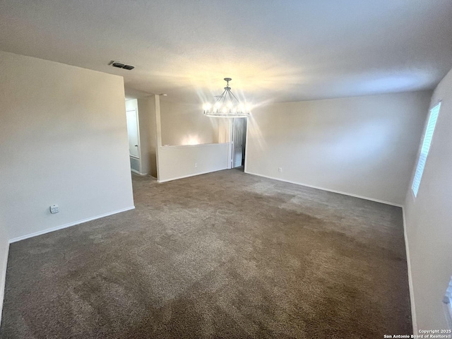 empty room featuring an inviting chandelier and dark colored carpet