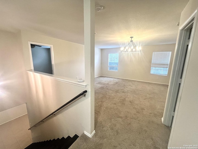 corridor with carpet floors and a notable chandelier