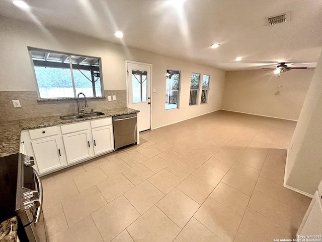 kitchen with tasteful backsplash, dark stone countertops, range, stainless steel dishwasher, and sink