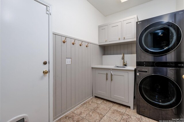 washroom featuring cabinets, sink, stacked washer and clothes dryer, and wooden walls