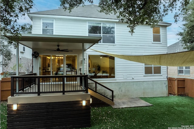 rear view of property with ceiling fan, a deck, and a yard