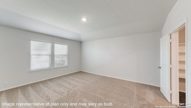 empty room featuring light carpet and vaulted ceiling