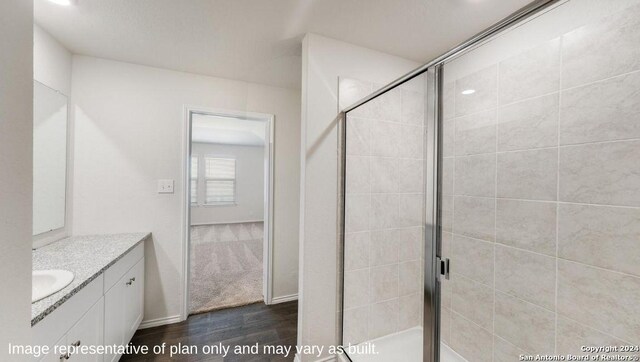 bathroom with an enclosed shower, vanity, and wood-type flooring