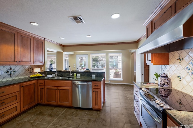 kitchen with dark stone countertops, kitchen peninsula, sink, stainless steel appliances, and ventilation hood