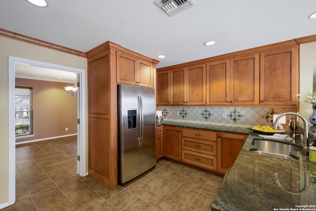 kitchen with tasteful backsplash, an inviting chandelier, sink, stainless steel fridge, and ornamental molding