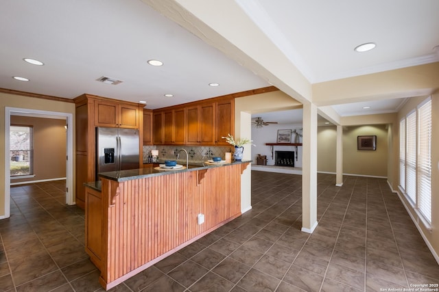 kitchen with tasteful backsplash, sink, stainless steel fridge, kitchen peninsula, and a breakfast bar