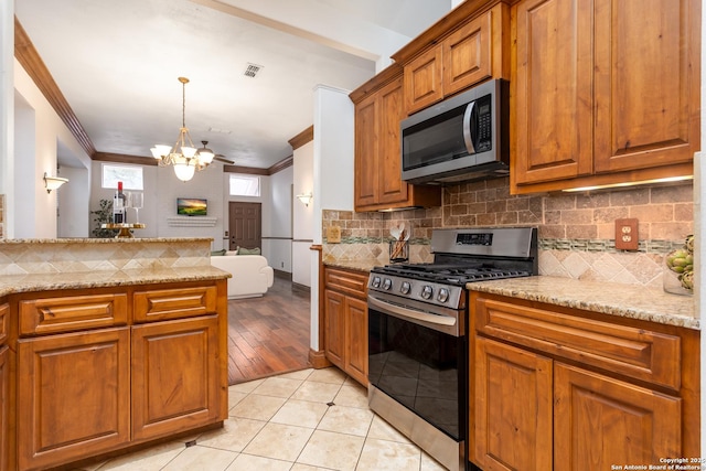 kitchen featuring light tile patterned flooring, crown molding, an inviting chandelier, light stone countertops, and stainless steel appliances