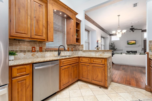 kitchen with a large fireplace, sink, appliances with stainless steel finishes, light tile patterned floors, and ceiling fan with notable chandelier