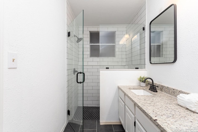 bathroom featuring a shower with door, vanity, and tile patterned flooring