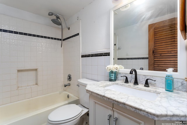 full bathroom featuring toilet, tile walls, vanity, and tiled shower / bath combo