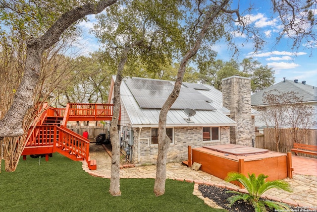 exterior space featuring a patio area, a hot tub, a yard, and a wooden deck