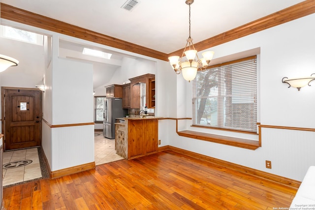 kitchen featuring a healthy amount of sunlight, kitchen peninsula, stainless steel fridge, and light hardwood / wood-style flooring