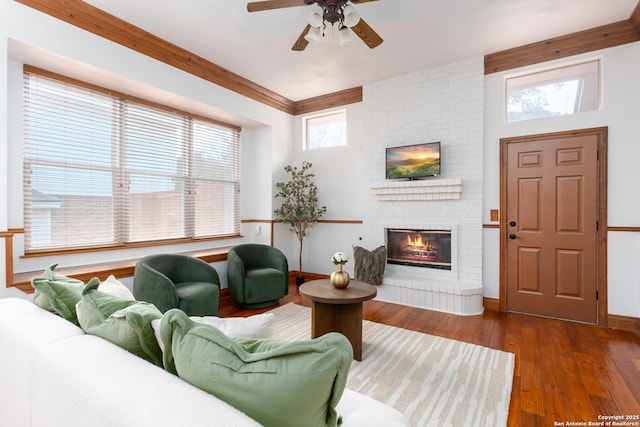 living room featuring ceiling fan, a wealth of natural light, dark hardwood / wood-style floors, and a brick fireplace