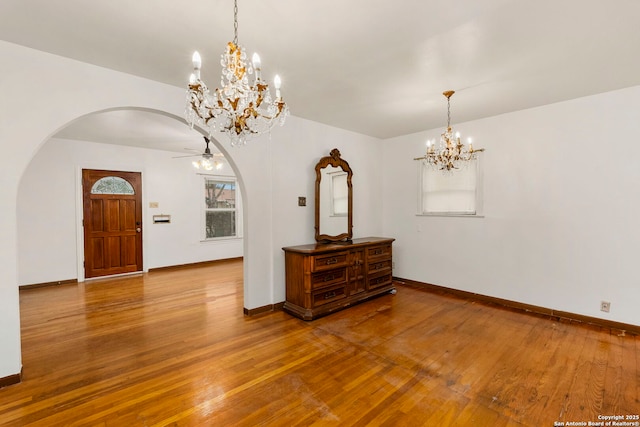 interior space with wood-type flooring and ceiling fan with notable chandelier