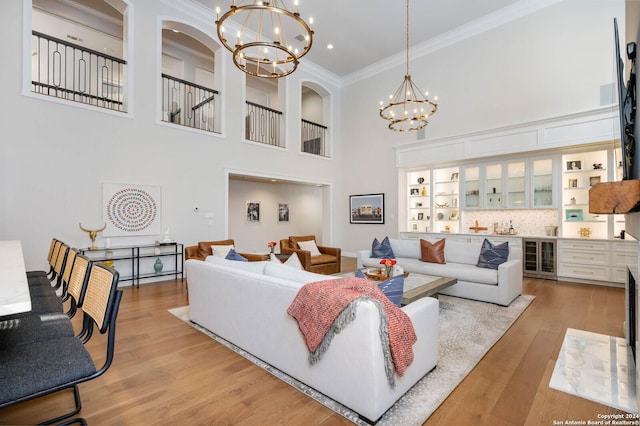 living room featuring light hardwood / wood-style flooring, crown molding, a chandelier, and wine cooler