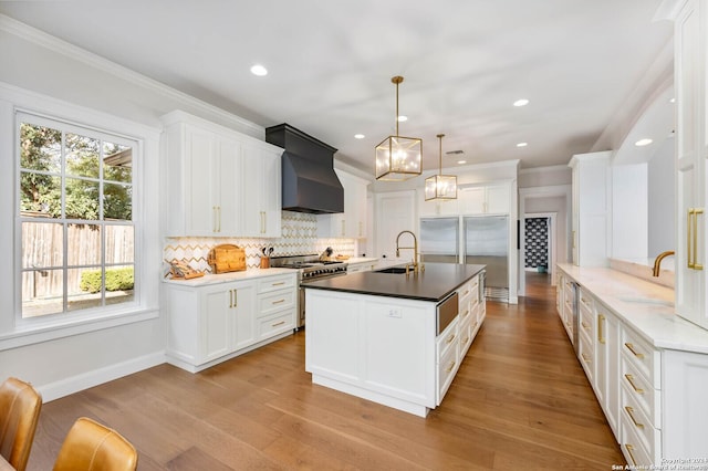 kitchen with premium range hood, sink, hanging light fixtures, and high end stove