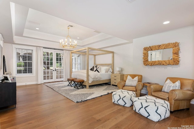 bedroom featuring access to outside, hardwood / wood-style flooring, a raised ceiling, and a notable chandelier