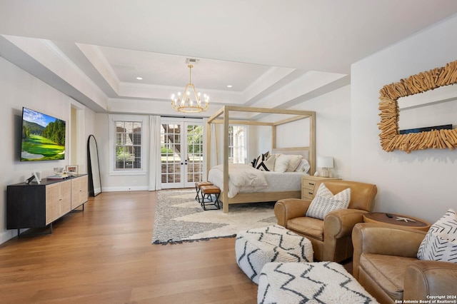 bedroom featuring access to exterior, a chandelier, french doors, and a tray ceiling