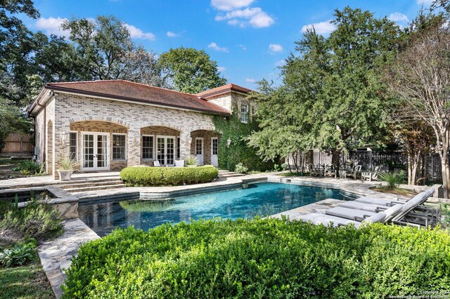 rear view of house featuring a fenced in pool, french doors, and a patio