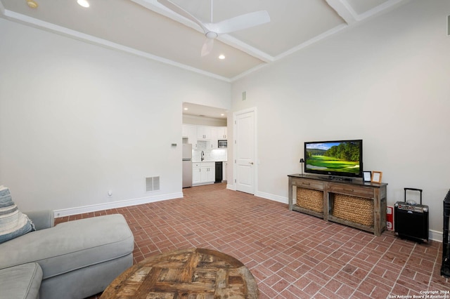 living room featuring ceiling fan, beam ceiling, a towering ceiling, and sink