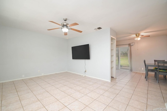 tiled empty room with ceiling fan and built in shelves