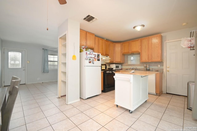 kitchen with a center island, black range oven, white refrigerator, backsplash, and light tile patterned floors