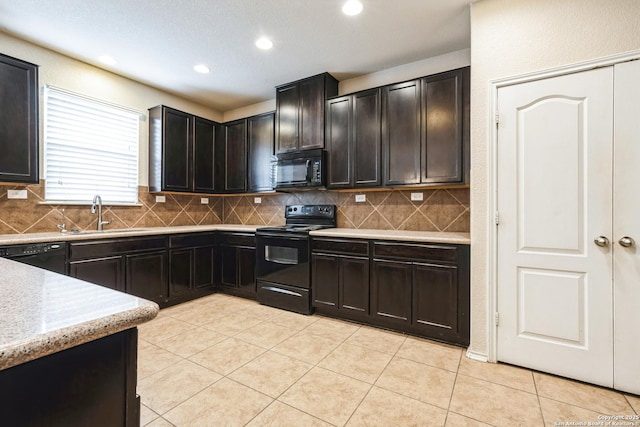 kitchen featuring black appliances, tasteful backsplash, sink, light tile patterned flooring, and light stone counters