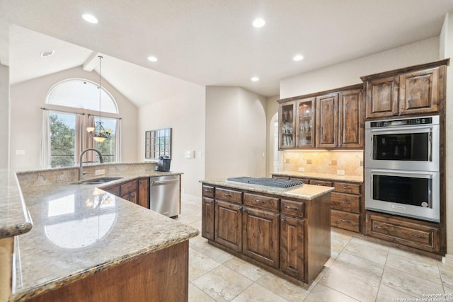 kitchen with a center island, vaulted ceiling with beams, decorative backsplash, sink, and appliances with stainless steel finishes