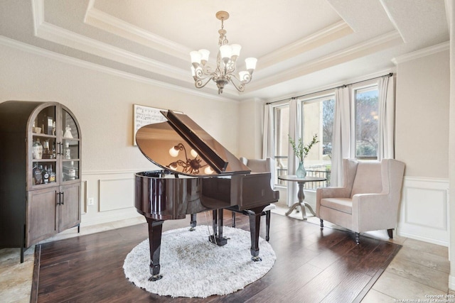 living area with an inviting chandelier, ornamental molding, wood-type flooring, and a tray ceiling