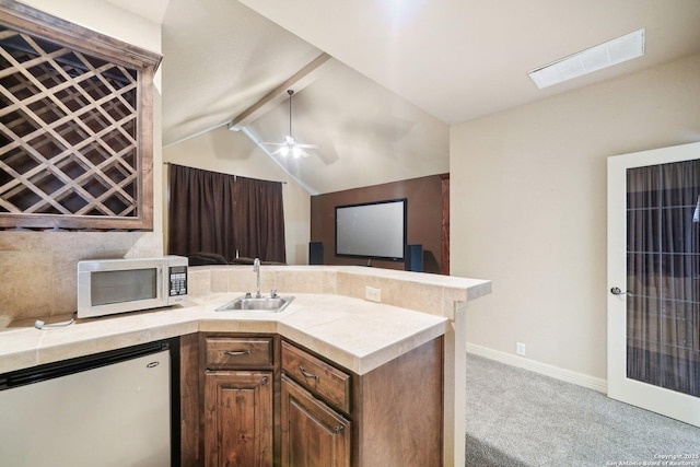 kitchen featuring ceiling fan, appliances with stainless steel finishes, light colored carpet, vaulted ceiling with beams, and sink