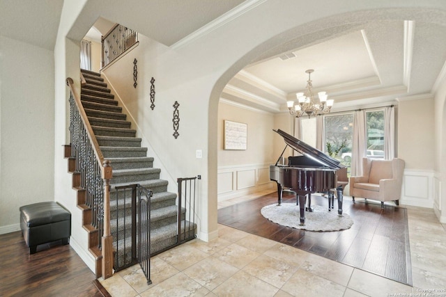 foyer entrance featuring an inviting chandelier, ornamental molding, and a tray ceiling