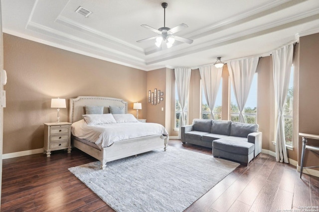 bedroom with ceiling fan, a tray ceiling, dark hardwood / wood-style flooring, and crown molding