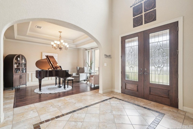 entryway with an inviting chandelier, crown molding, french doors, and a tray ceiling