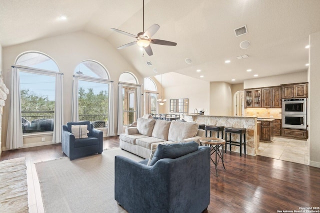 living room with ceiling fan, high vaulted ceiling, and light wood-type flooring