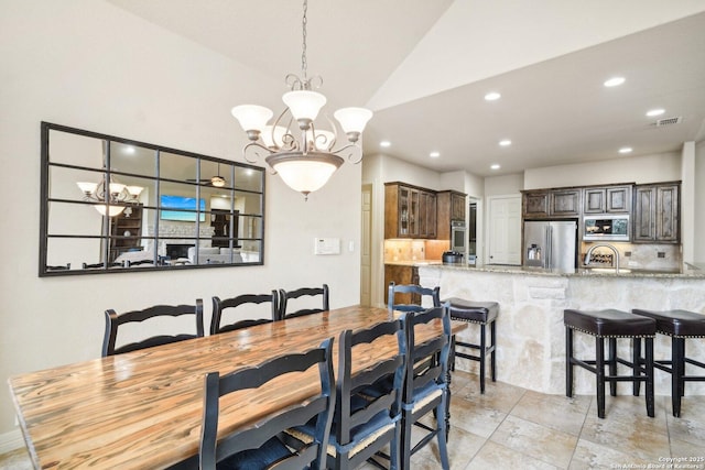 dining space featuring sink, lofted ceiling, and a notable chandelier