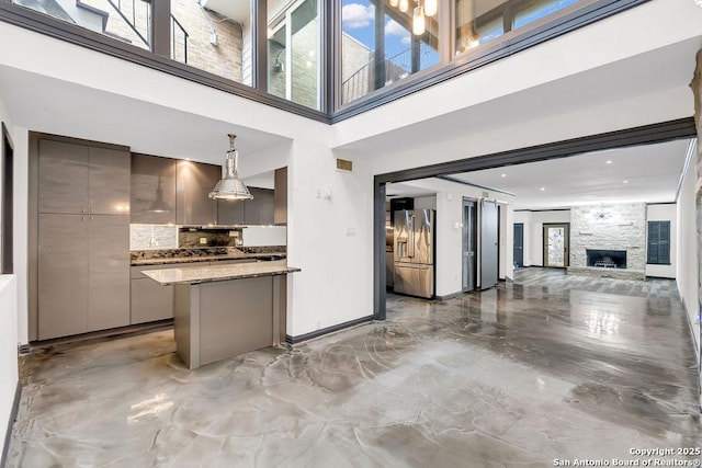 kitchen with tasteful backsplash, a fireplace, high quality fridge, hanging light fixtures, and gray cabinetry