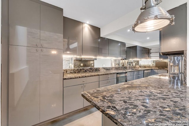 kitchen featuring decorative light fixtures, backsplash, dark stone counters, and gray cabinetry