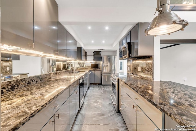 kitchen featuring gray cabinets, appliances with stainless steel finishes, backsplash, dark stone countertops, and sink