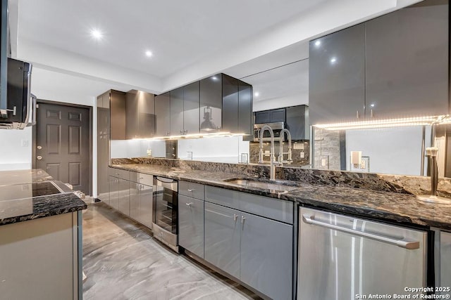 kitchen featuring dark stone countertops, stainless steel dishwasher, sink, gray cabinetry, and beverage cooler