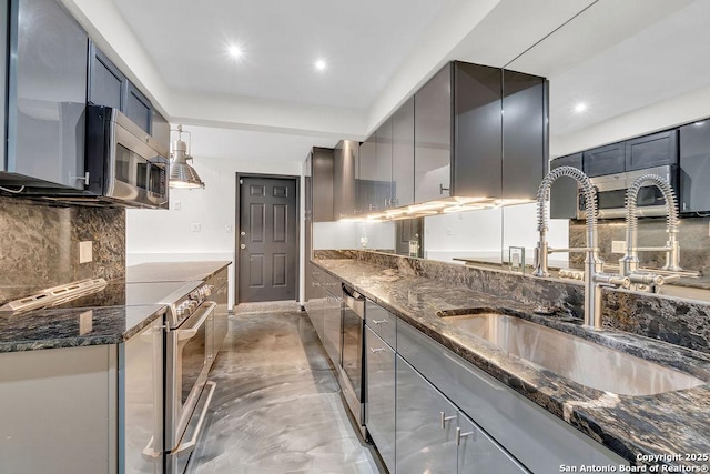 kitchen with stainless steel appliances, decorative backsplash, dark stone counters, and sink