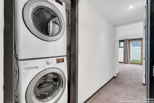 laundry area featuring stacked washer and dryer and light carpet