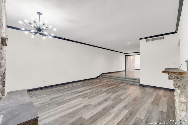 unfurnished living room with crown molding, light hardwood / wood-style floors, and a notable chandelier