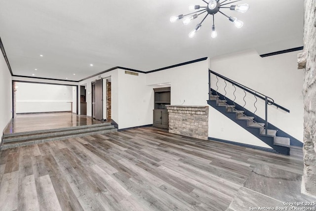 unfurnished living room featuring light hardwood / wood-style flooring, ornamental molding, and a chandelier