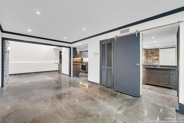 unfurnished living room featuring crown molding and a barn door