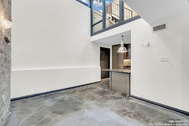 unfurnished living room with a high ceiling and concrete floors