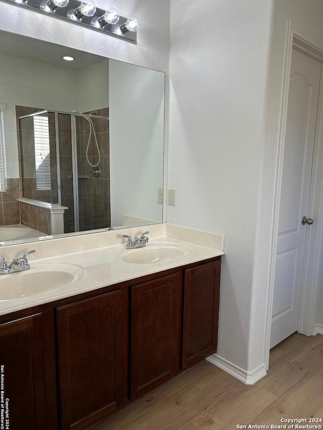 bathroom featuring walk in shower, vanity, and wood-type flooring