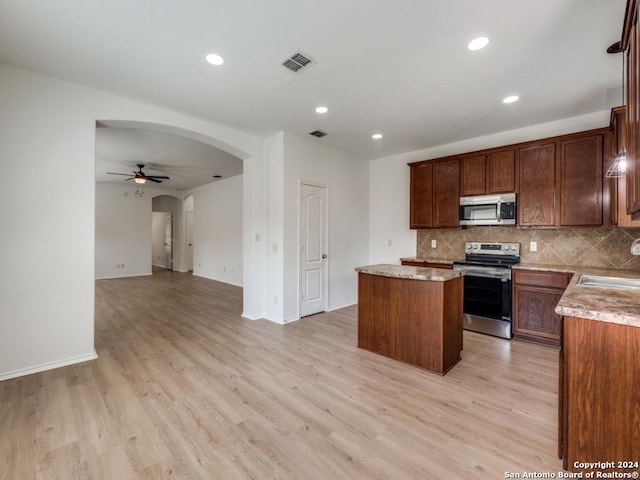 kitchen featuring ceiling fan, backsplash, a center island, light wood-type flooring, and stainless steel appliances