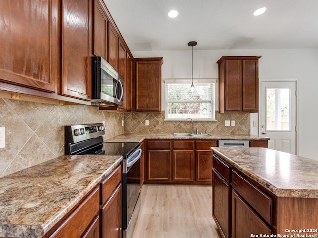 kitchen with sink, a wealth of natural light, stainless steel appliances, and light wood-type flooring