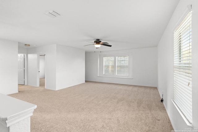 empty room with light carpet, ceiling fan, and a wealth of natural light