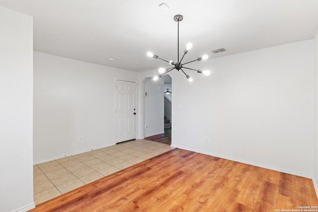 empty room featuring light tile patterned floors and a chandelier